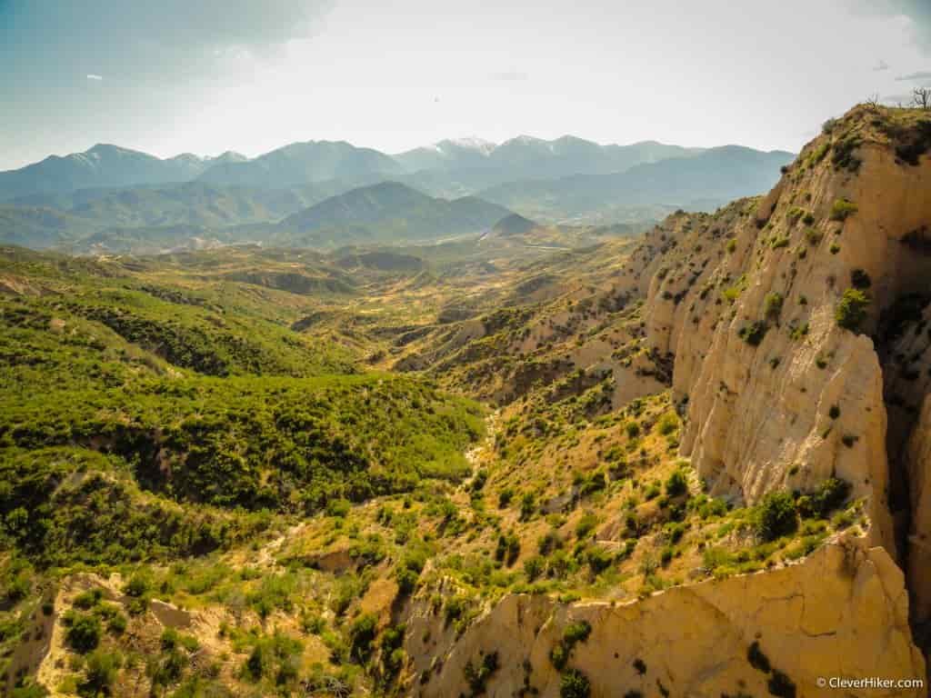 Looking down on light-colored mountains with trees and waves of mountains in the background