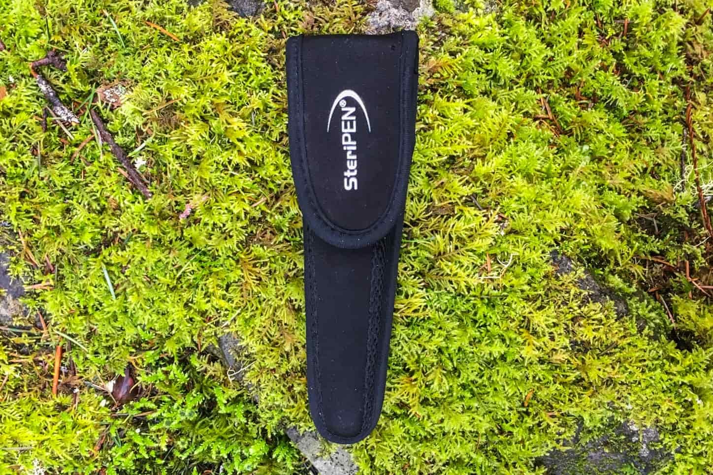 the steripen sheathed in its case resting on top of bright green moss