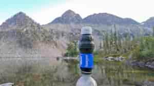 Closeup of the Sawyer Squeeze water filter in front of an alpine lake