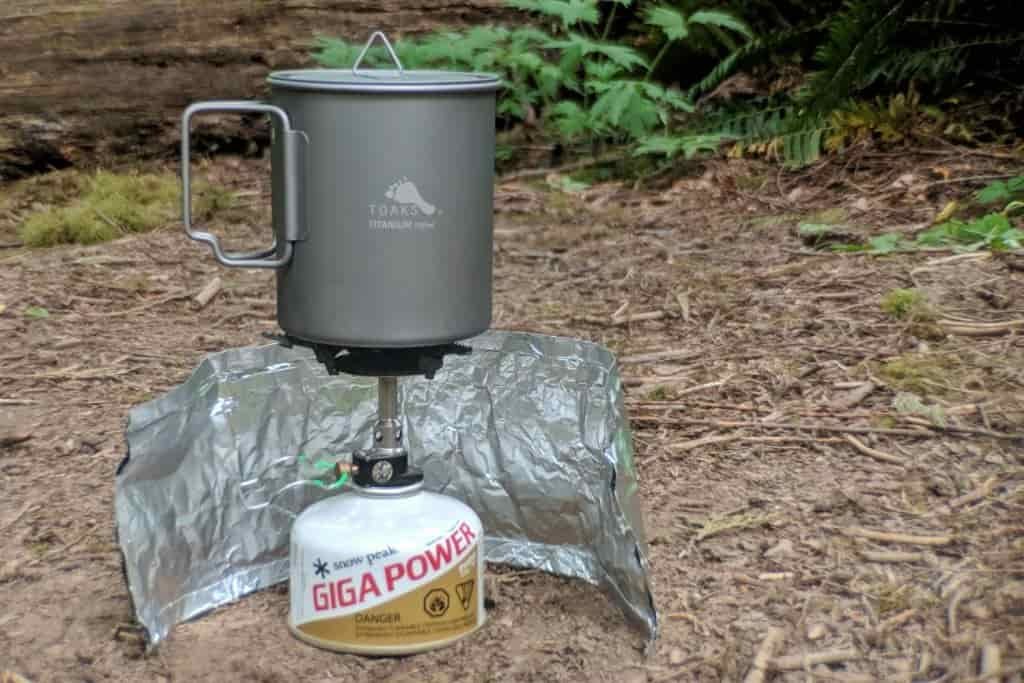 a backpacking stove set up with a windscreen
