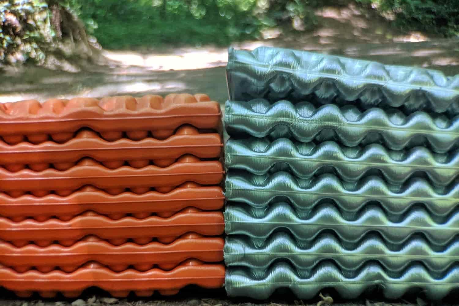 two closed cell foam sleeping pads folded up on the ground