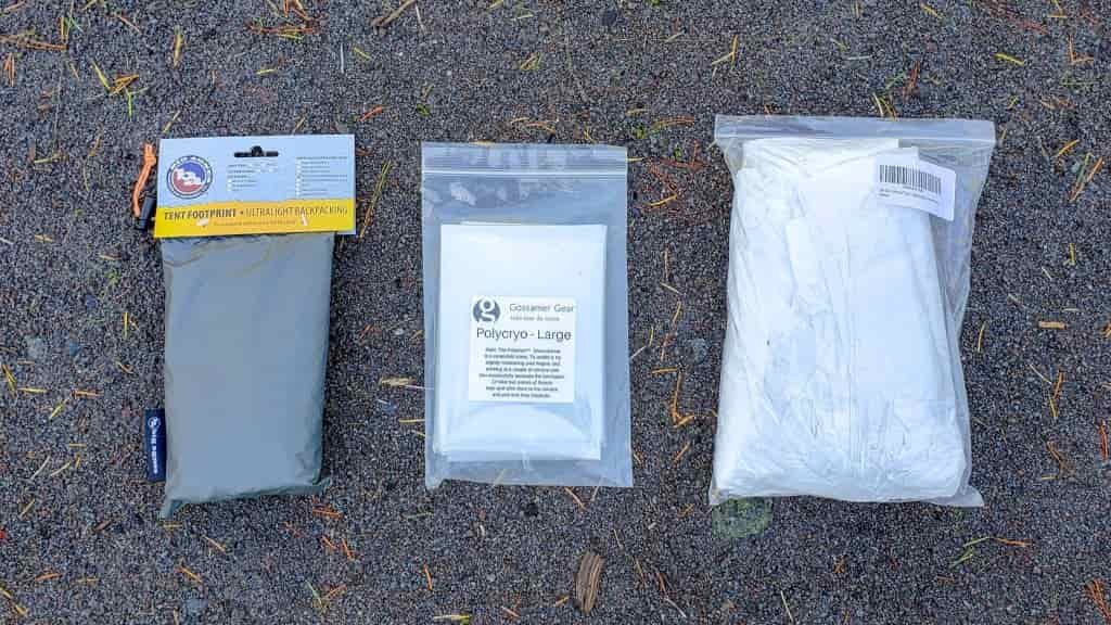 3 packs of footprint material next to each other on the ground: a manufacturer's footprint, a bag of polycryo, and a bag of tyvek