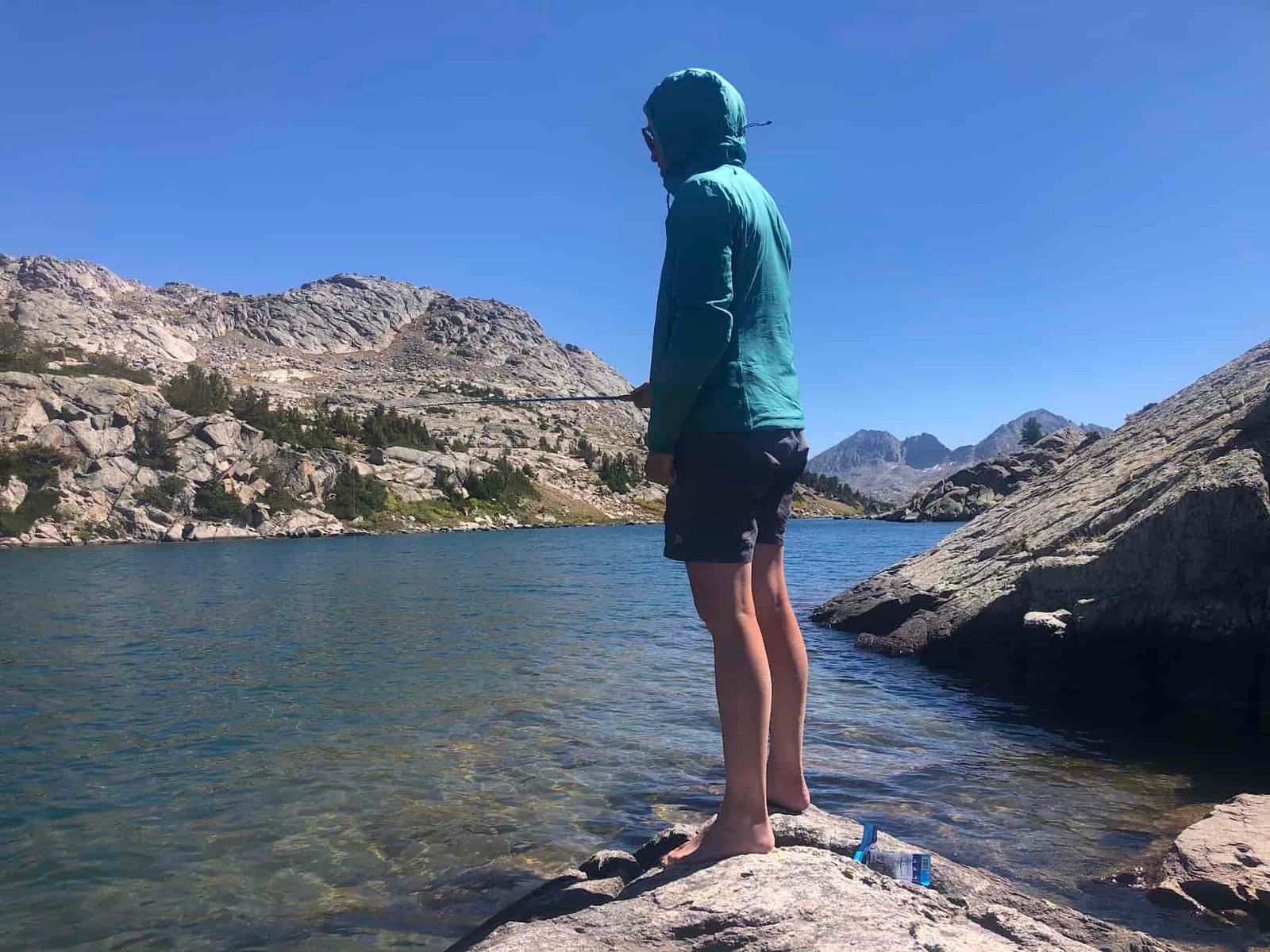 woman fishing into a clear blue lake on a sunny day in the wind river range