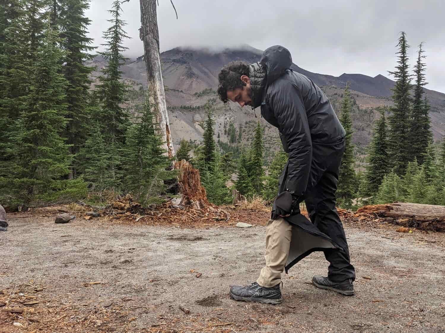 A hiker zipping up the REI Rainier Full Zip Rain Pants