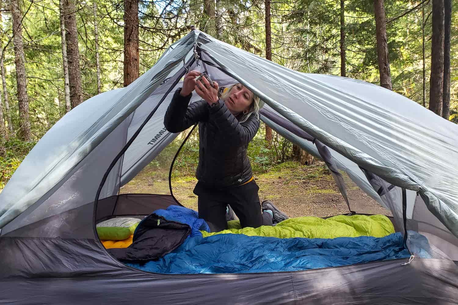 A hiker in the doorway of the Sea to Summit Telos TR2 backpacking tent installing the Lightbar