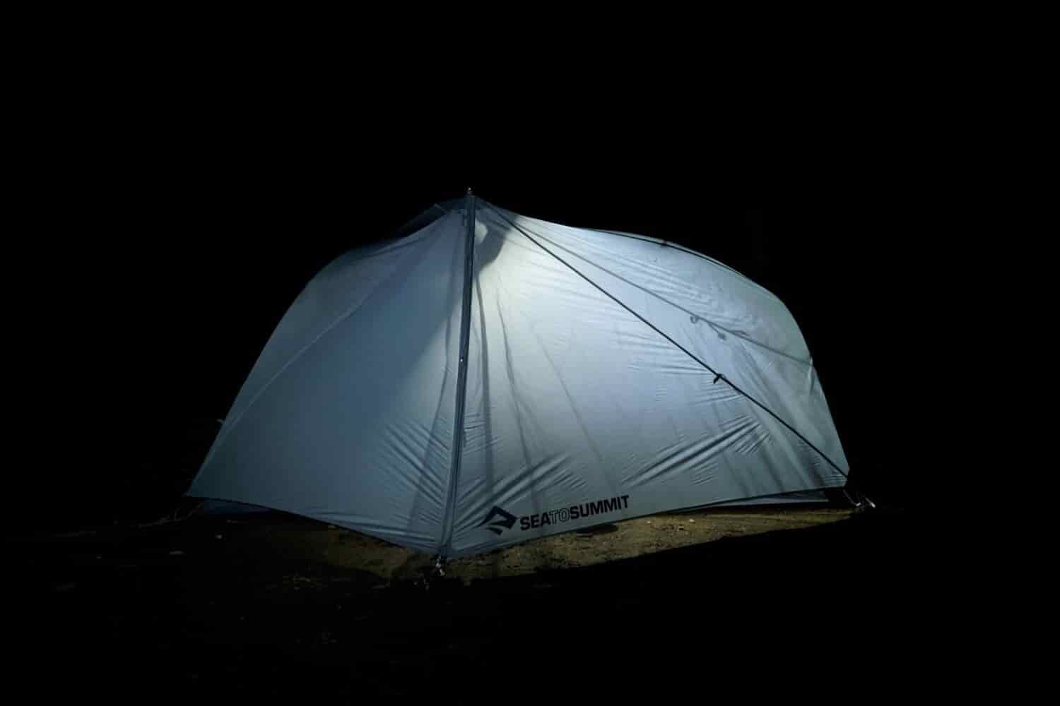 a backpacking tent with a light on inside at night
