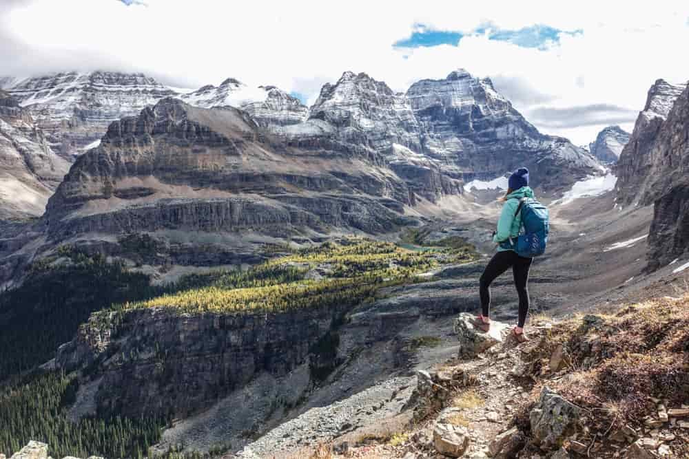 A day hiker with a full day pack looks out over a mountain valley