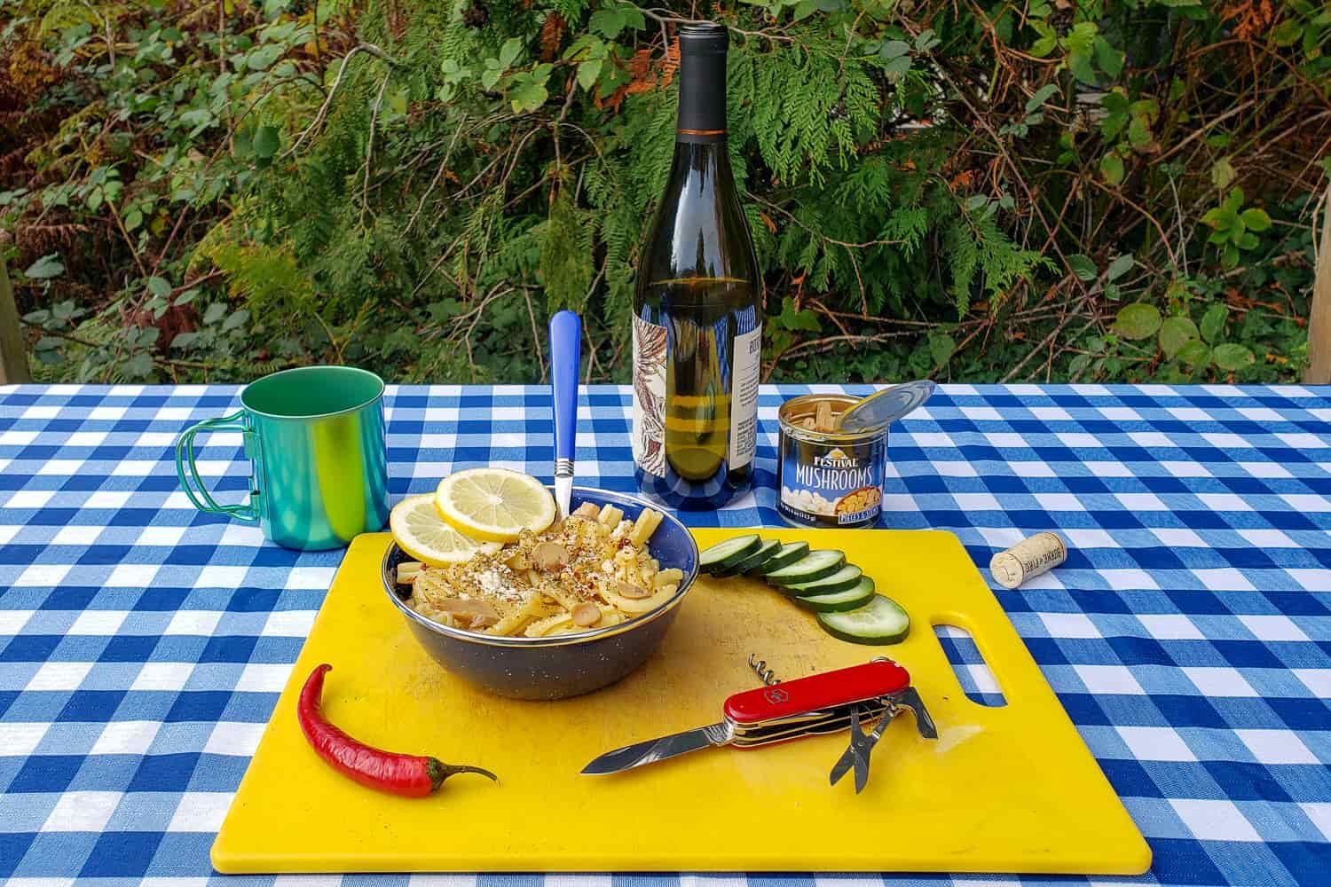 a camp picnic set up on a picnic table with a swiss army knife deployed