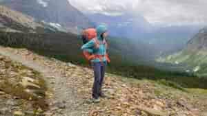 A backpacker wearing the Black Diamond Alpine Start Windbreaker while hiking in Glacier National Park in June