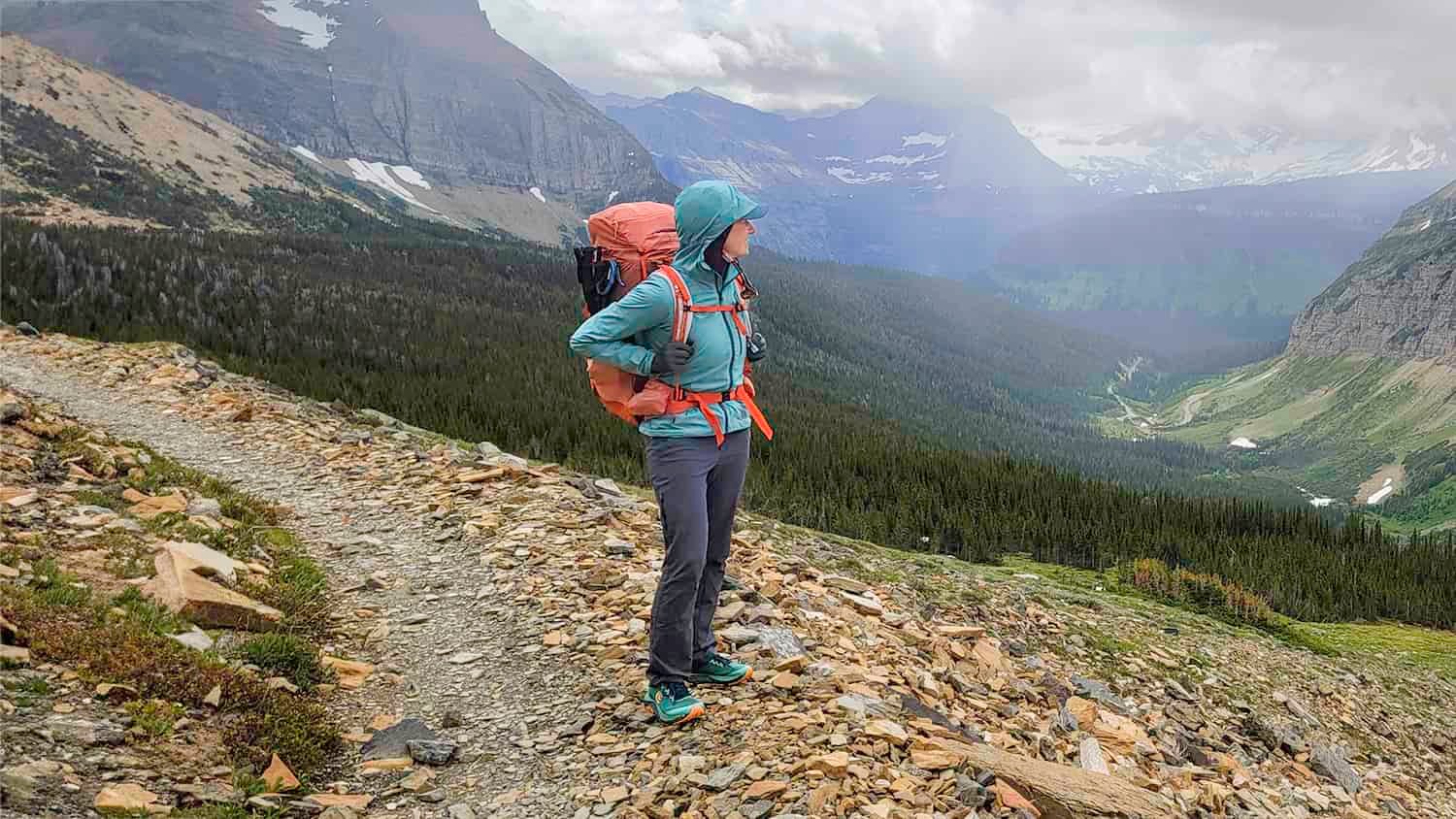 A backpacker wearing the Black Diamond Alpine Start Windbreaker while hiking in Glacier National Park in June