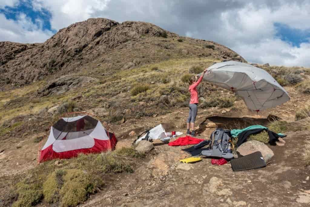 person airing out a rain fly while backpacking on a ridge