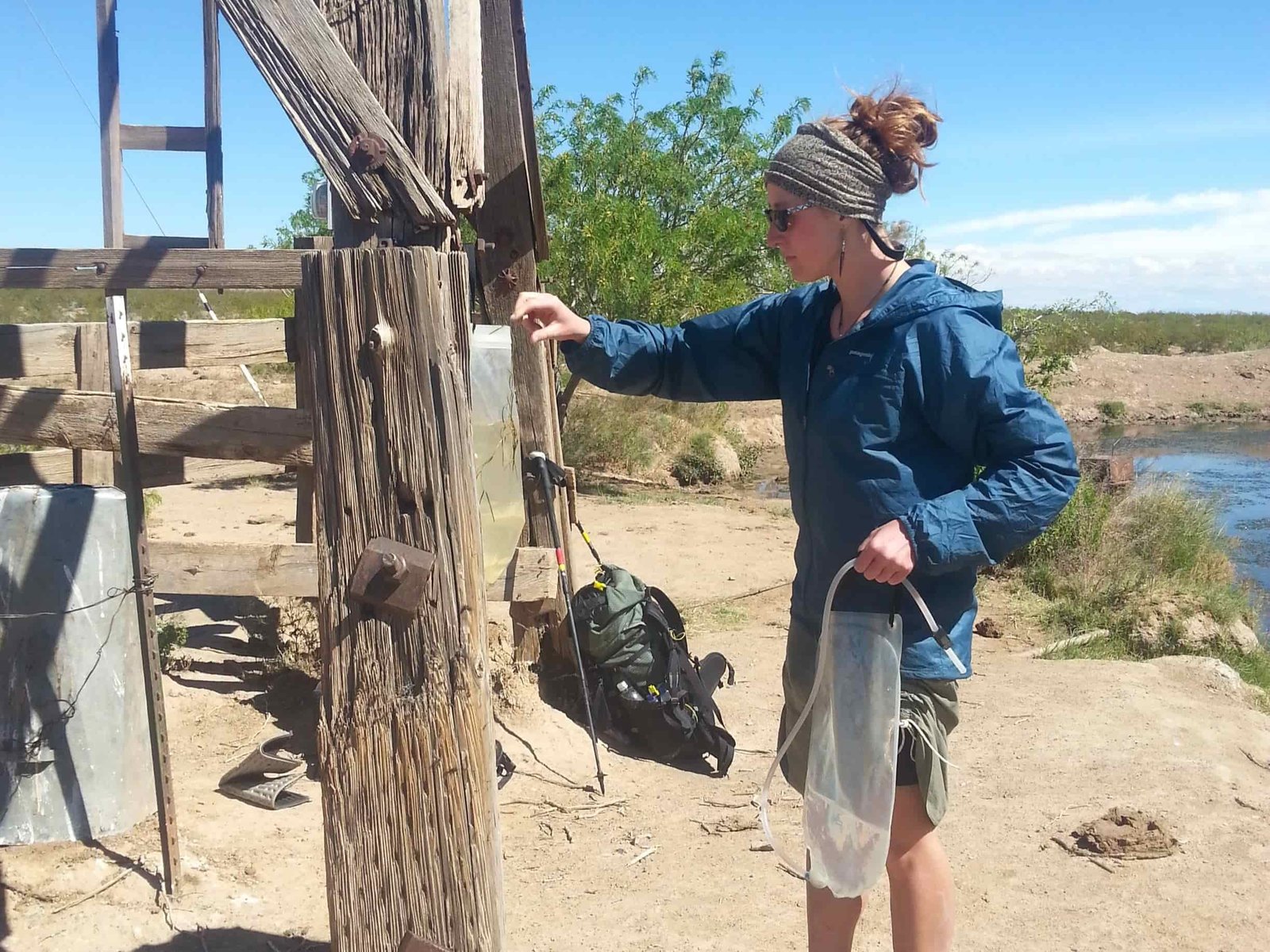a cdt backpacker hangs their platypus gravityworks from a wooden ranch structure