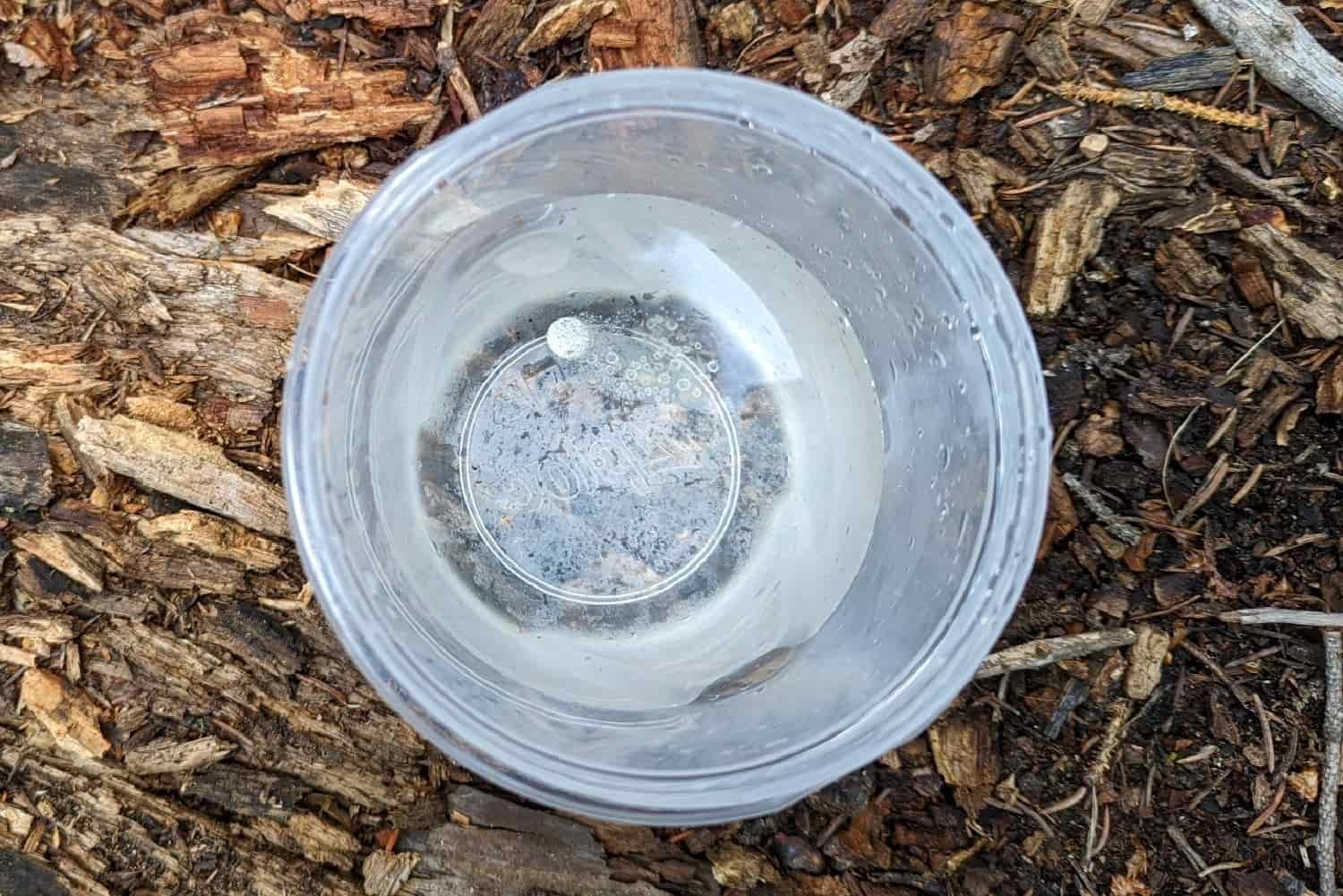 a cup of water with a micropur chlorine water purifying tablet at the bottom beginning to treat the water