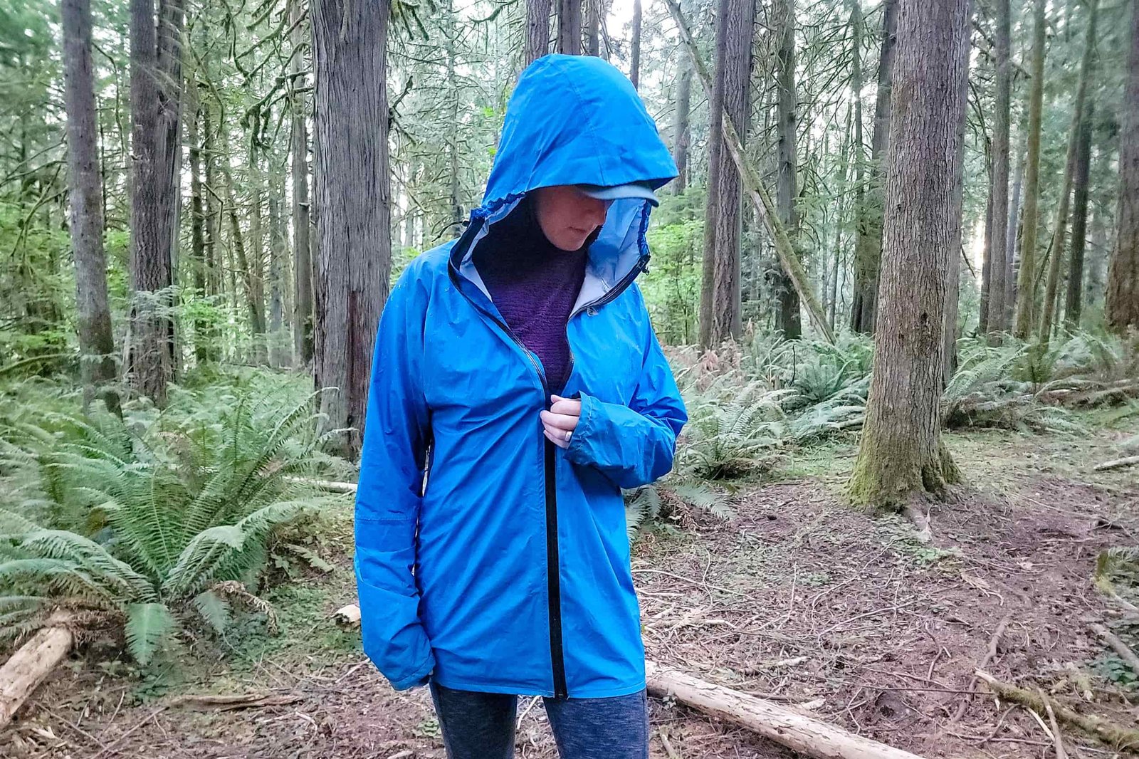 a hiker unzipping their zpacks vertice rain jacket in the woods