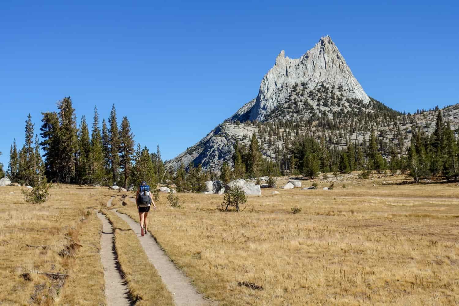Backpacker walking towards a granite spire on the John Muir Trail