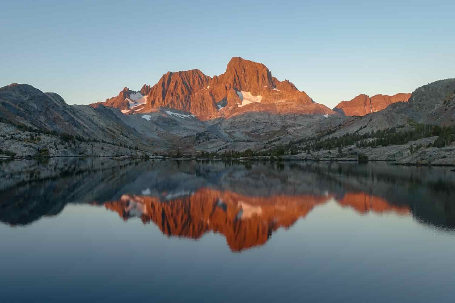 sunset alpenglow on a craggy peak reflecting on a still lake