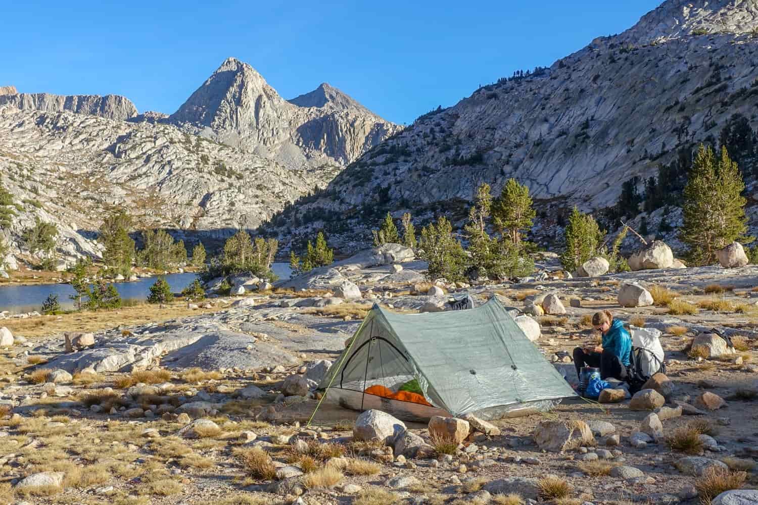 Backpacker on the JMT in their campsite with their tent pitched.