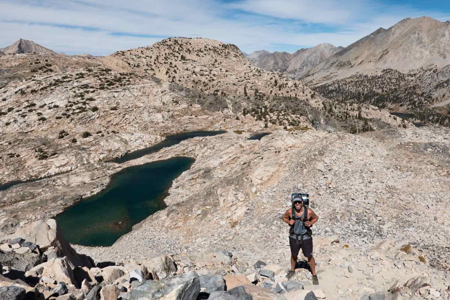 Backpacker posing above alpine lakes on the John Muir Trail