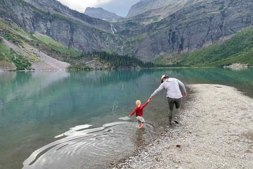 Mother walks with child hand in hand through a mountain lake