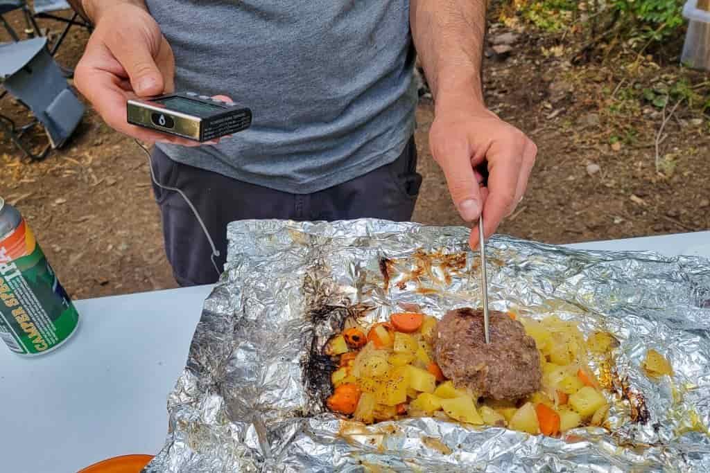 camper takes the temperature of its burger