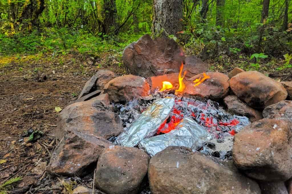 campfire with foil packet meals cooking
