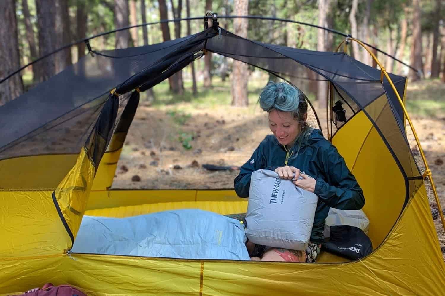 a backpacker with their hands pressing on the NeoAir Xtherm NXT pump sack to inflate their therm-a-rest