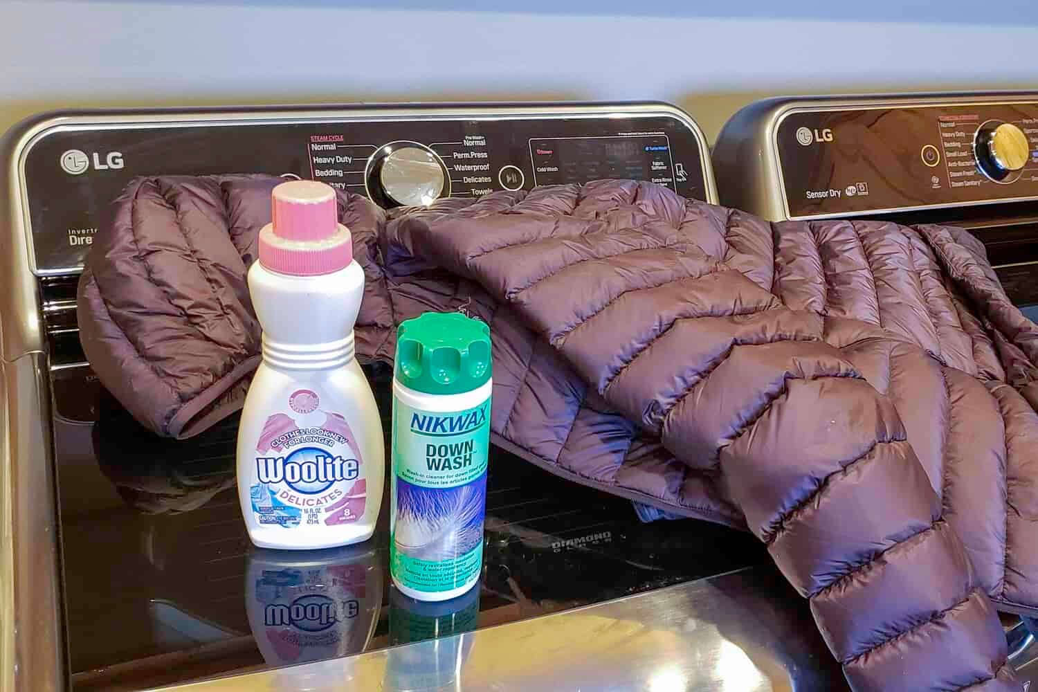 A down jacket and some technical fabric wash sitting on a washing machine