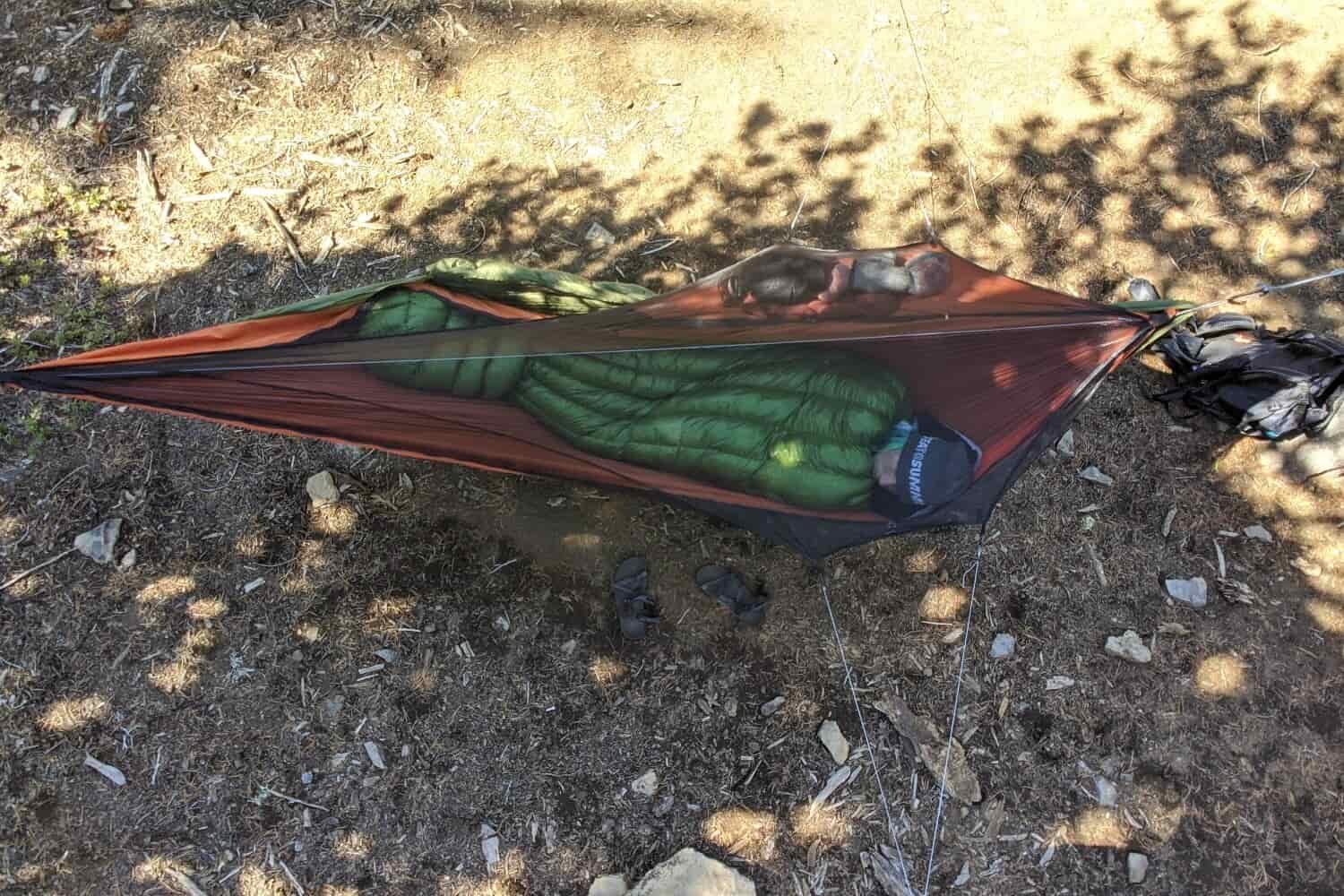 A hiker laying in a backpacking hammock