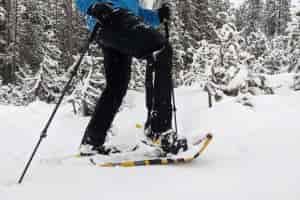 a man walking through snow in the atlas montane snowshoe