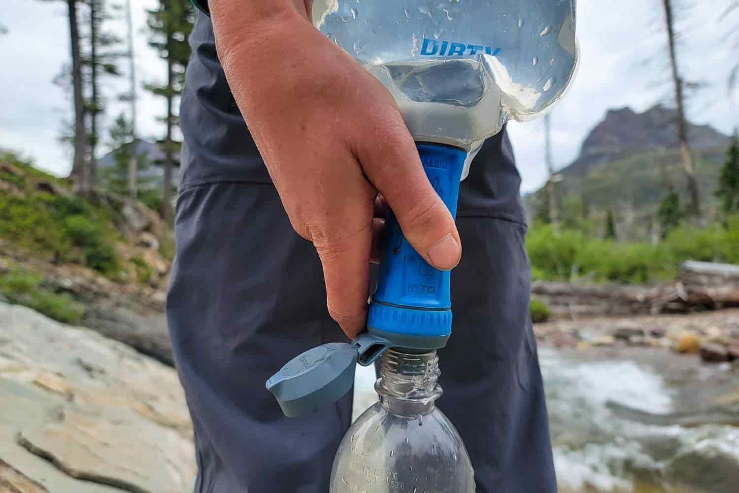 Closeup of the Platypus QuickDraw with a backpacker holding the squeeze filter over a waterbottle and guiding the filtered water into a bottle
