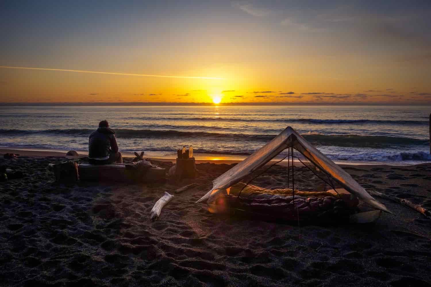 The Zpacks Triplex tent on the beach with a sunset in the background