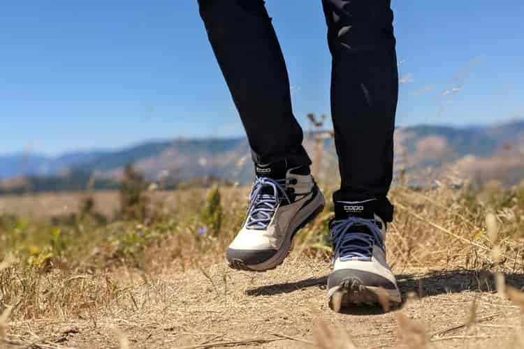Close up of lightweight hiking boots as a hiker walks across a grassy field 