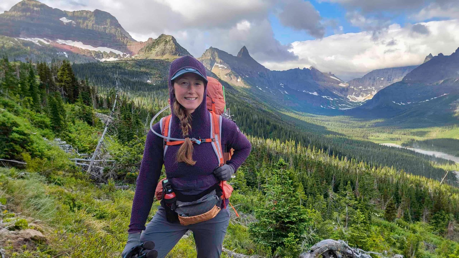 A female backpacker wearing the Eddie Bauer Super Sevens Fleece Pullover in front of jagged mountain peaks in Glacier National Park
