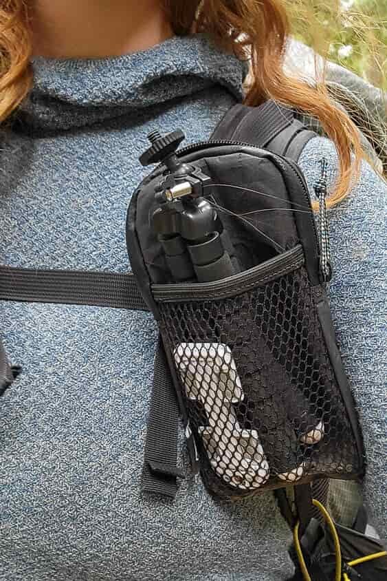 Close up of a mesh pocket on the shoulder strap of a backpack that holds a small cellphone tripod