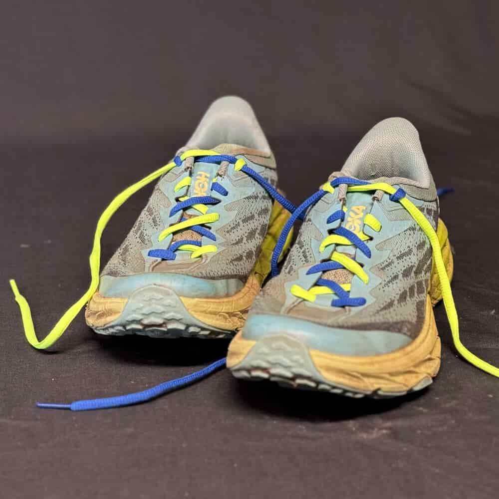 Dual-colored shoelaces demonstrating heel-lock lacing on the women's HOKA Speedgoat trail running shoes