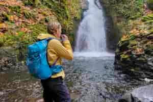 A hiker in front of a waterfall with the Gregory Juno 24 H2O hydration pack