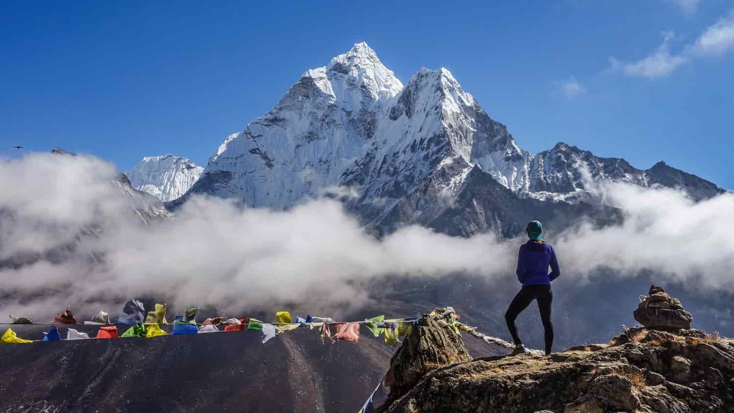 A hiker stands on an overlook looking at the Himalayas in Nepal
