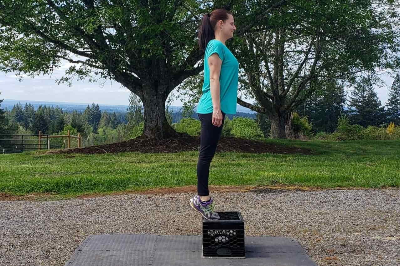 A woman stands on a milk crate on her toes with her heels elevated