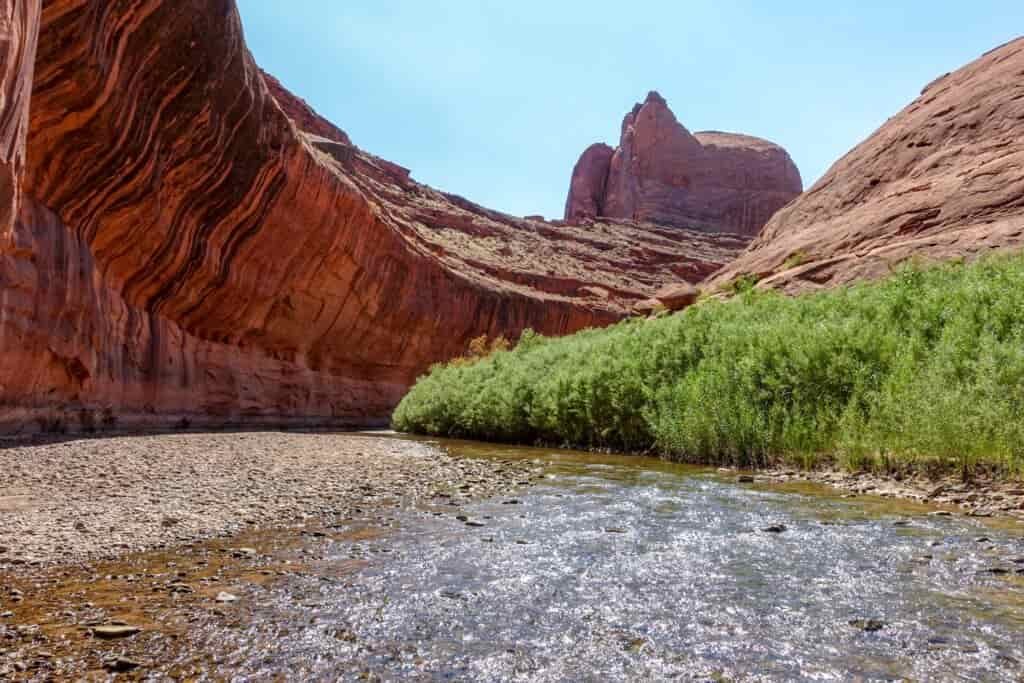an overhanging rock structure shades a shallow river