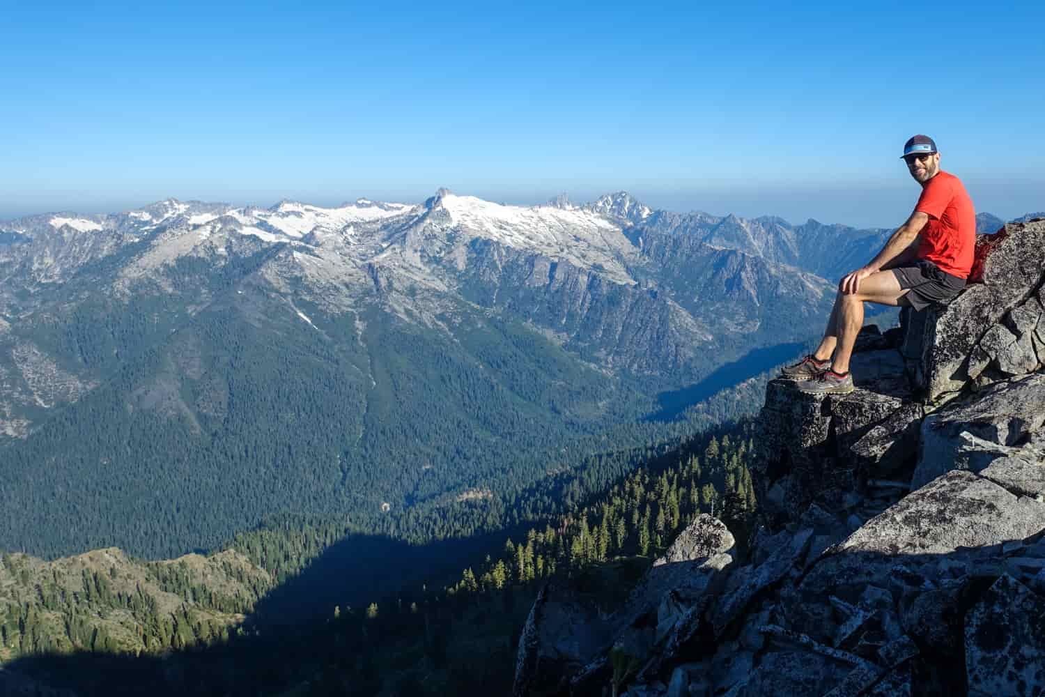 backpacker perched on a rock overlooking the trinity alps in california
