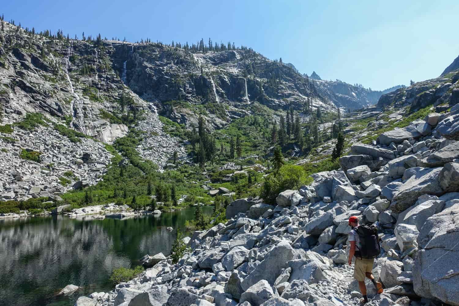 backpacker in the trinity alps along a scree field leading to an alpine lake