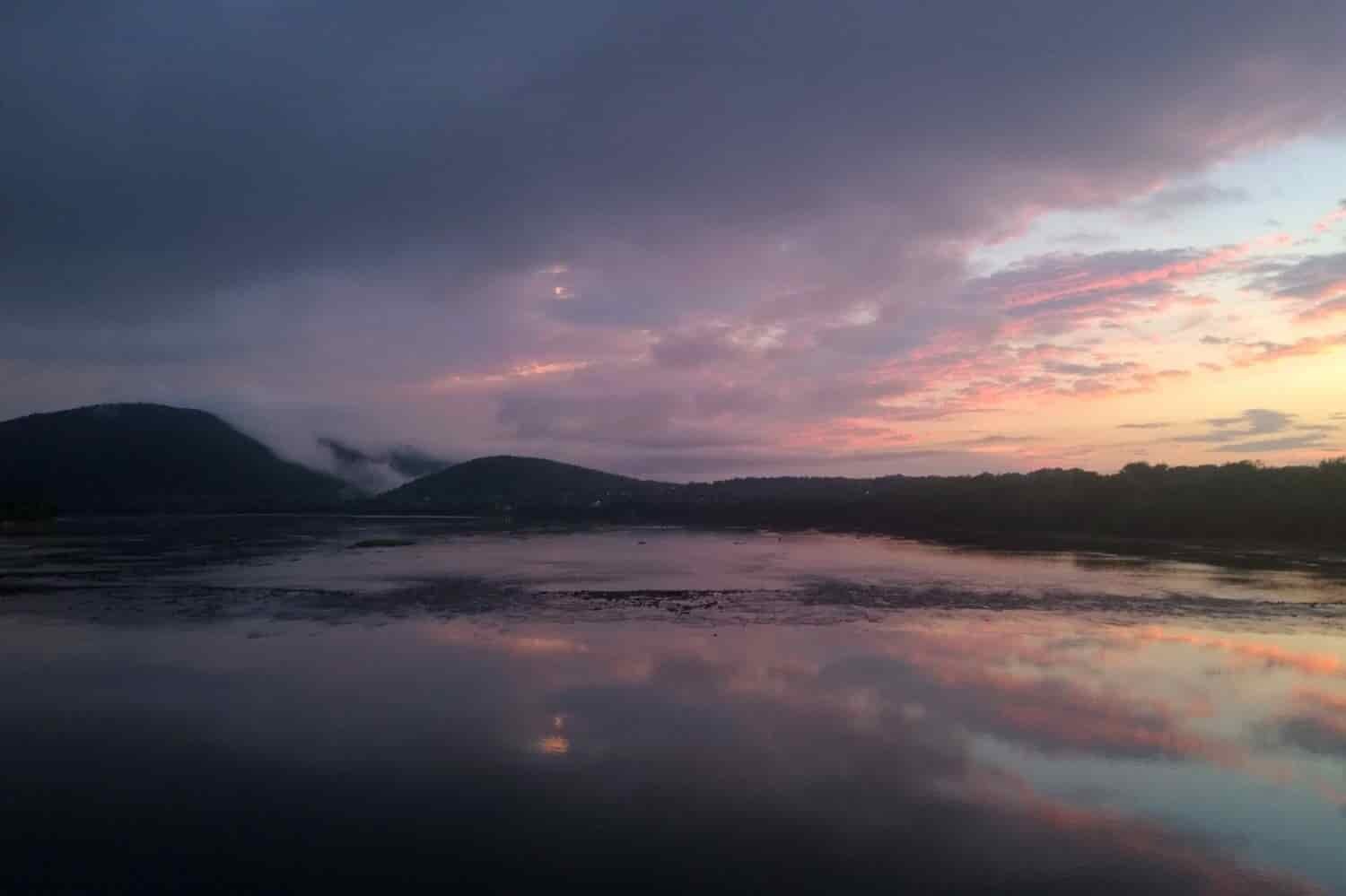 cloudy pink, orange and gray sunset over a lake