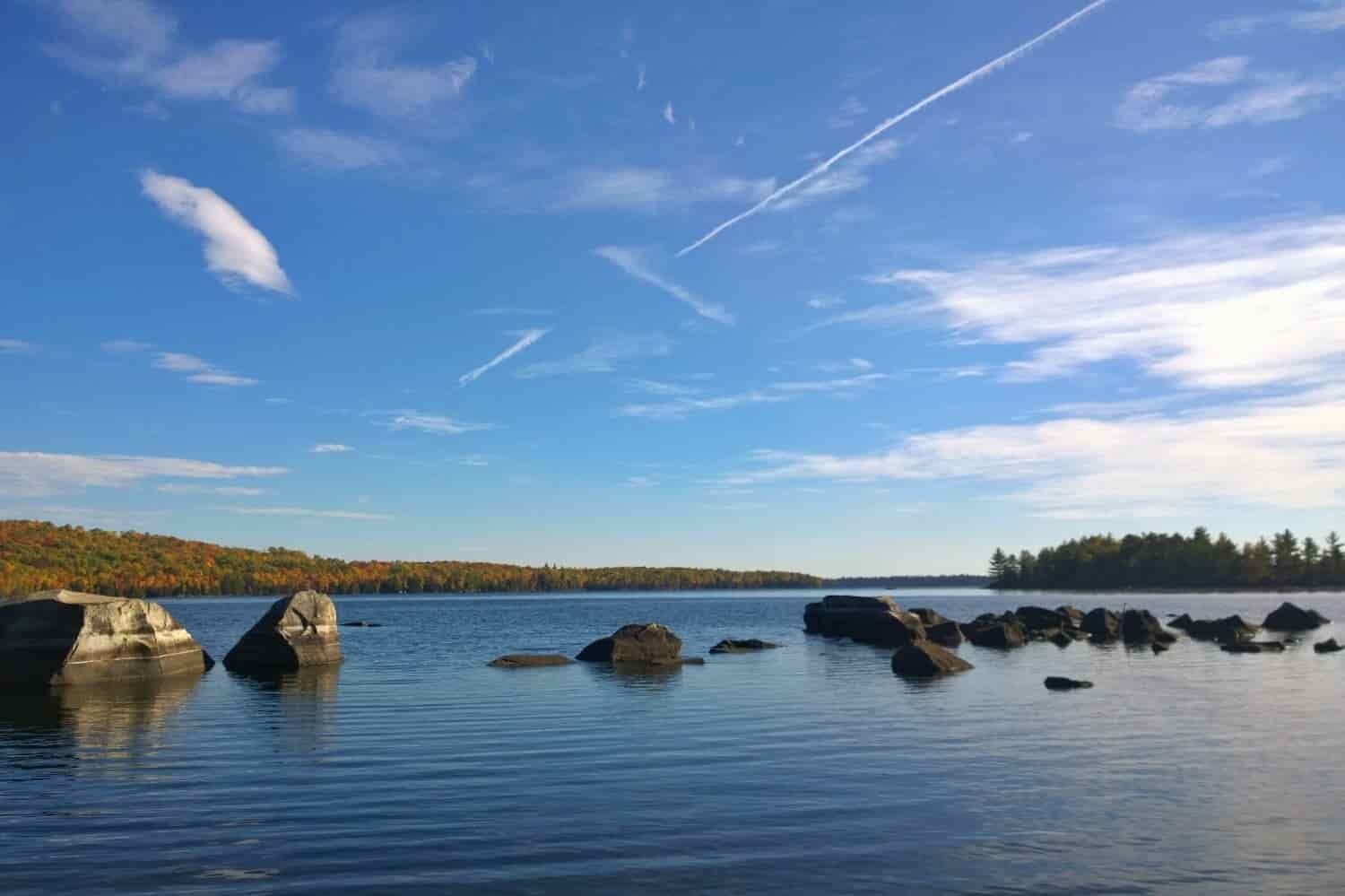 Sunny lake in New England with boulders peaking out of the water