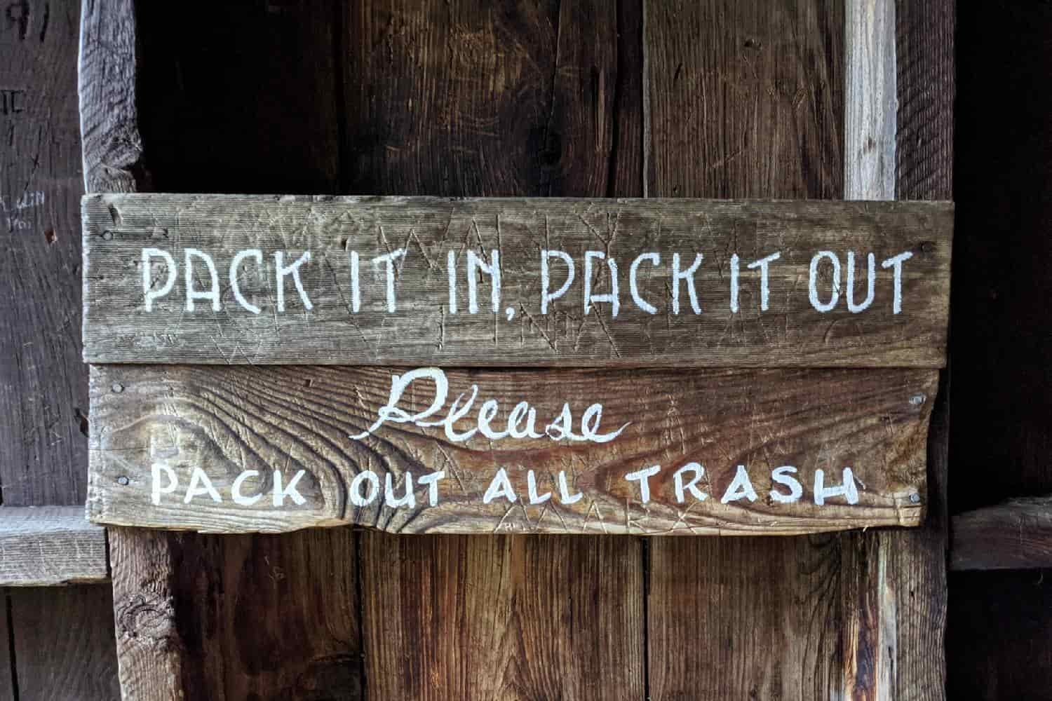 wooden sign on an Appalachian Trail shelter stating, "Pack it in, pack it out. Pack out all trash."