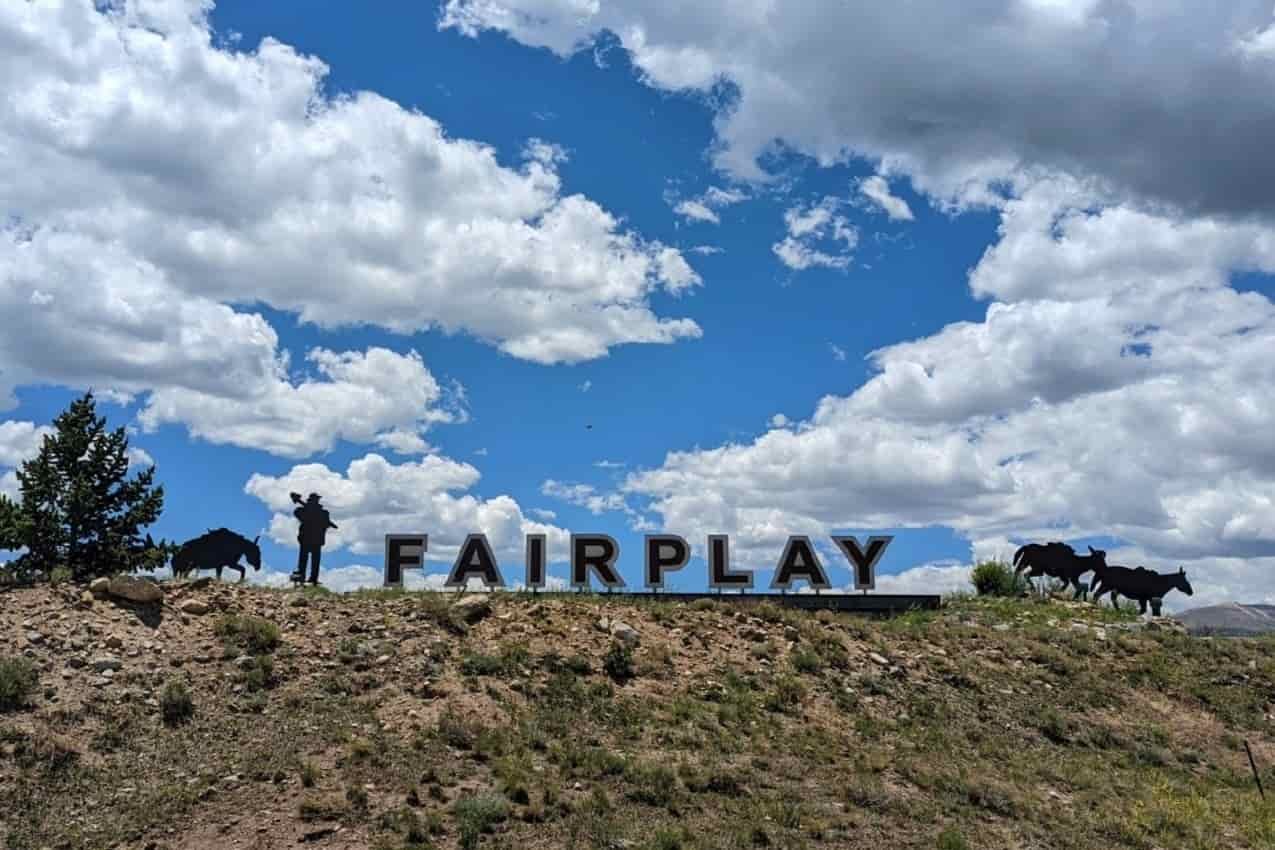town sign that says fairplay with steel cutouts of a miner, a donkey, mules and a cow