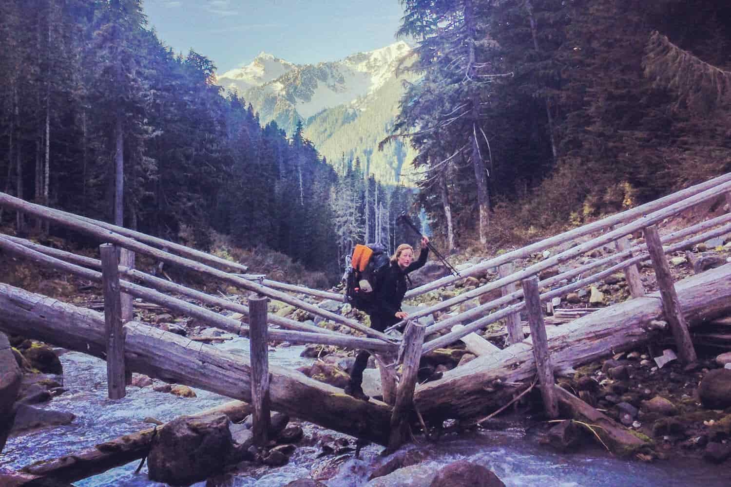 Thru-hiker on the PCT crossing a partially collapsed foot bridge