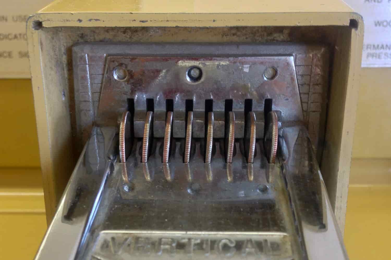 Quarters filling the coin slot of a washing machine at the laundromat.