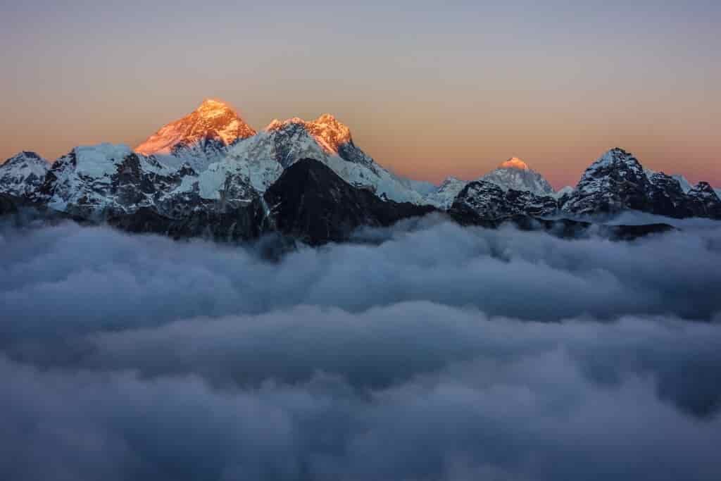 Looking down on clouds with sun lighting several mountains peaking through the haze 