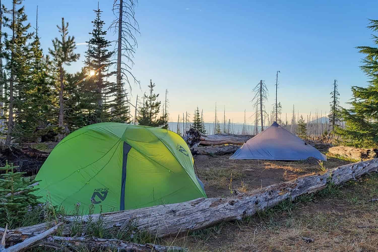 two tents pitched in the glowing evening light near booth lake in the central oregon cascades