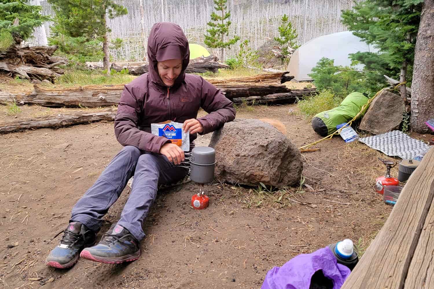 Backpacker making breakfast in camp while hiking around Three fingered jack